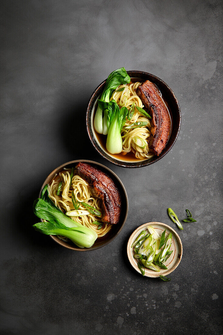 Ramen, pork belly and bok choy with a black background