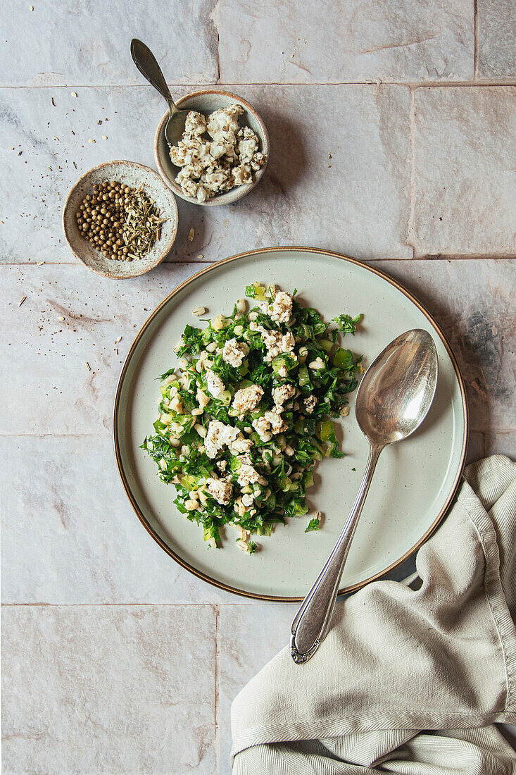 Parsley and barley salad with marinated feta on tiled background
