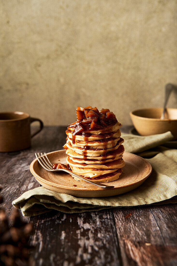 Apfel-Zimt-Pfannkuchenstapel auf Holzoberfläche und salbeigrünem Hintergrund