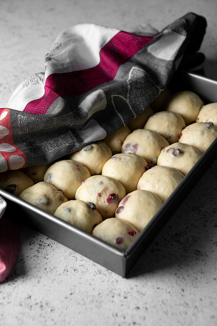 Cranberry hot cross buns on a baking tray