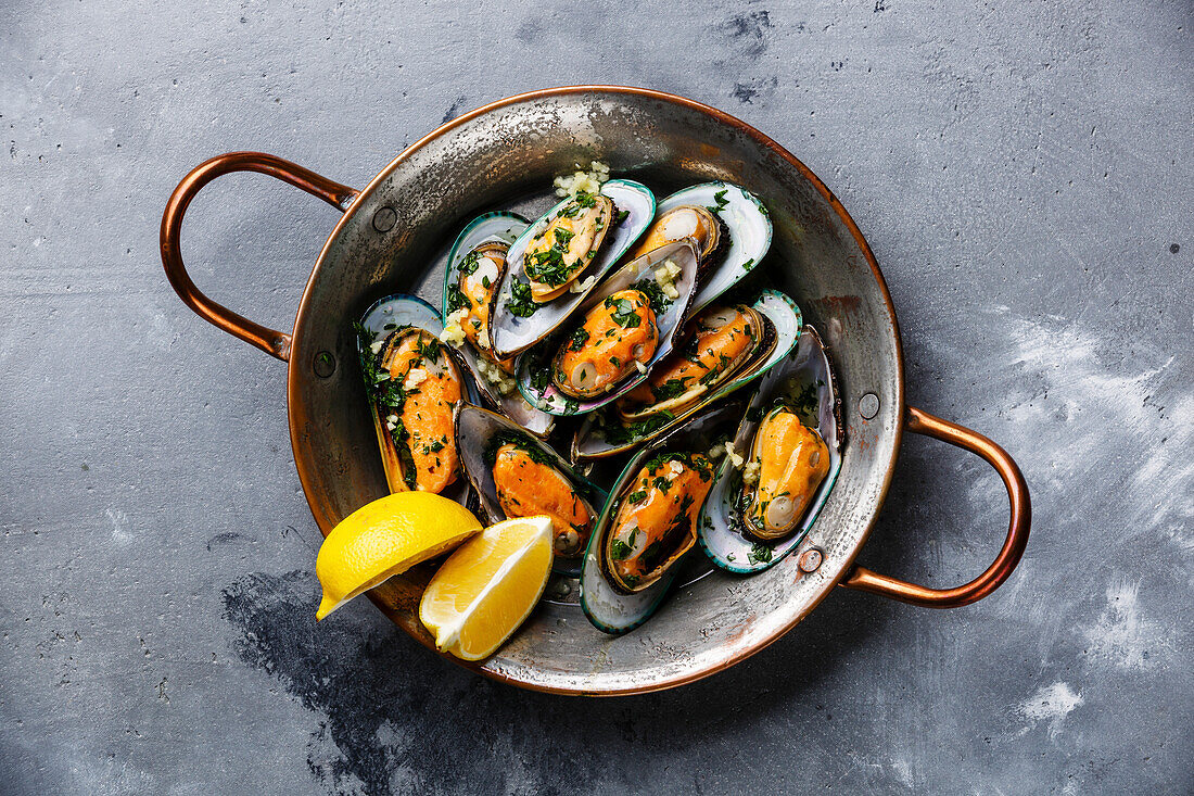 Mussels Mussels in a copper pan with parsley and lemon on a concrete background