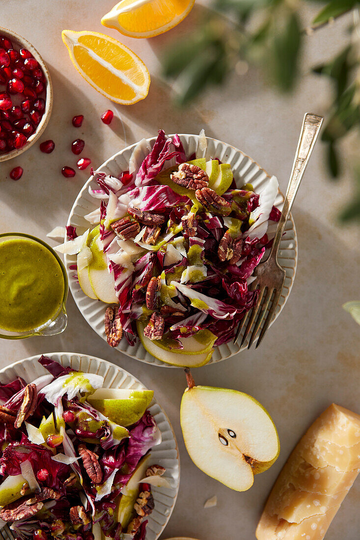 Radicchio-Salat mit Birnen, Pekannüssen, Granatapfel, Pekannüssen und Basilikum-Vinaigrette auf neutralem braunen Hintergrund mit grünem Tuch