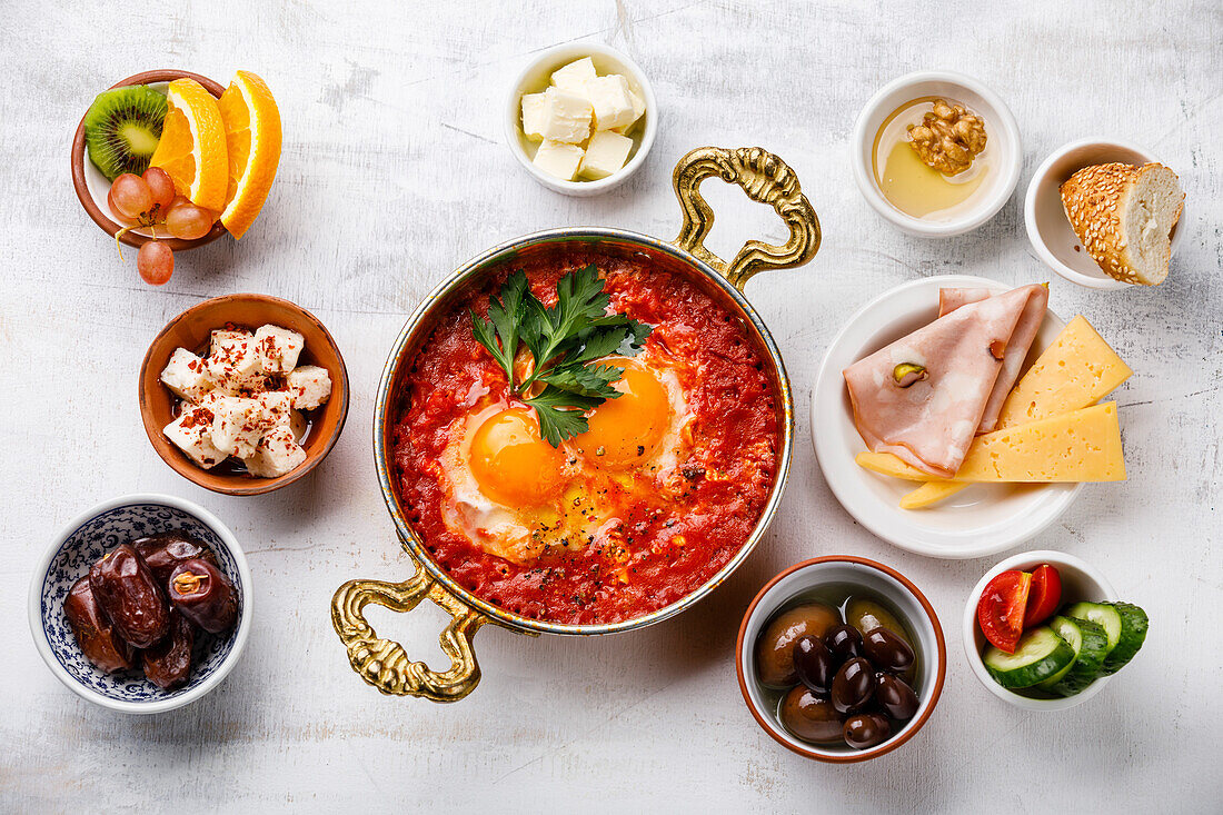 Spiegelei mit Tomaten in einer Kupferpfanne und verschiedenen Frühstückssnacks auf weißem Hintergrund
