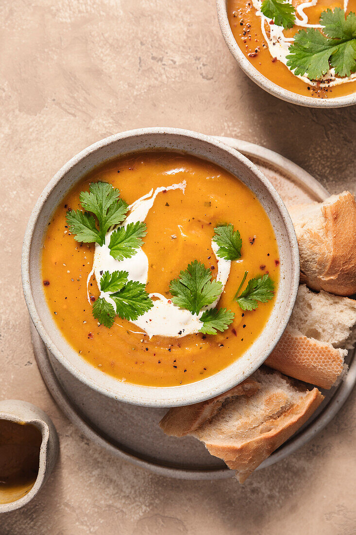 Butternut squash soup and baguette on a ceramic plate