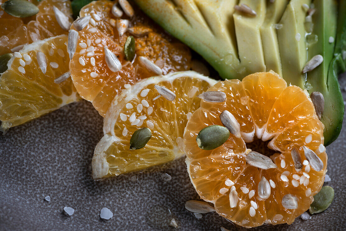 Salat mit Avocado, Mandarinen, Orangen, Rucola und verschiedenen Körnern. Nahaufnahme