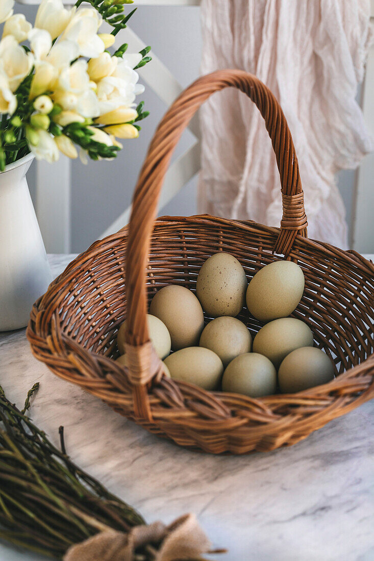 Green eggs in a wicker basket on a white marble table