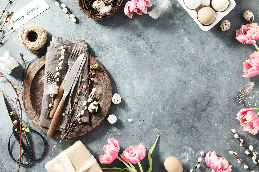 Easter table with spring flowers and cutlery on dark blue background, top view, laid flat. Happy Easter concept for cafes and restaurants. Copy space
