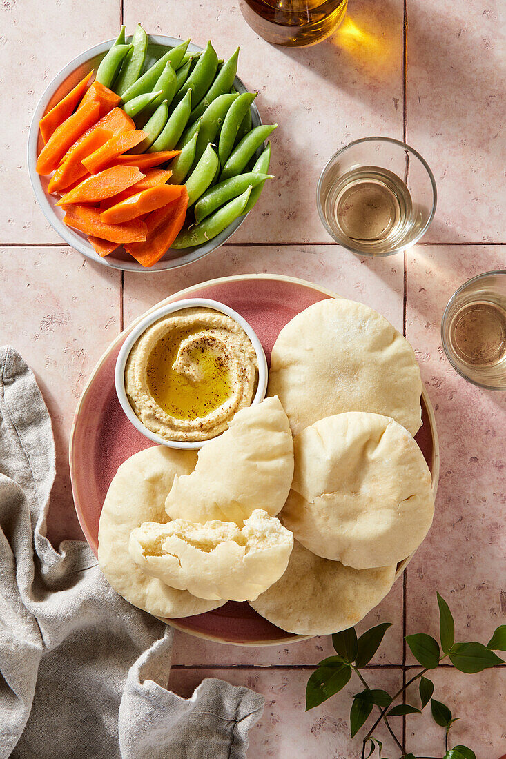 Fladenbrot und Hummus auf rosa Fliese