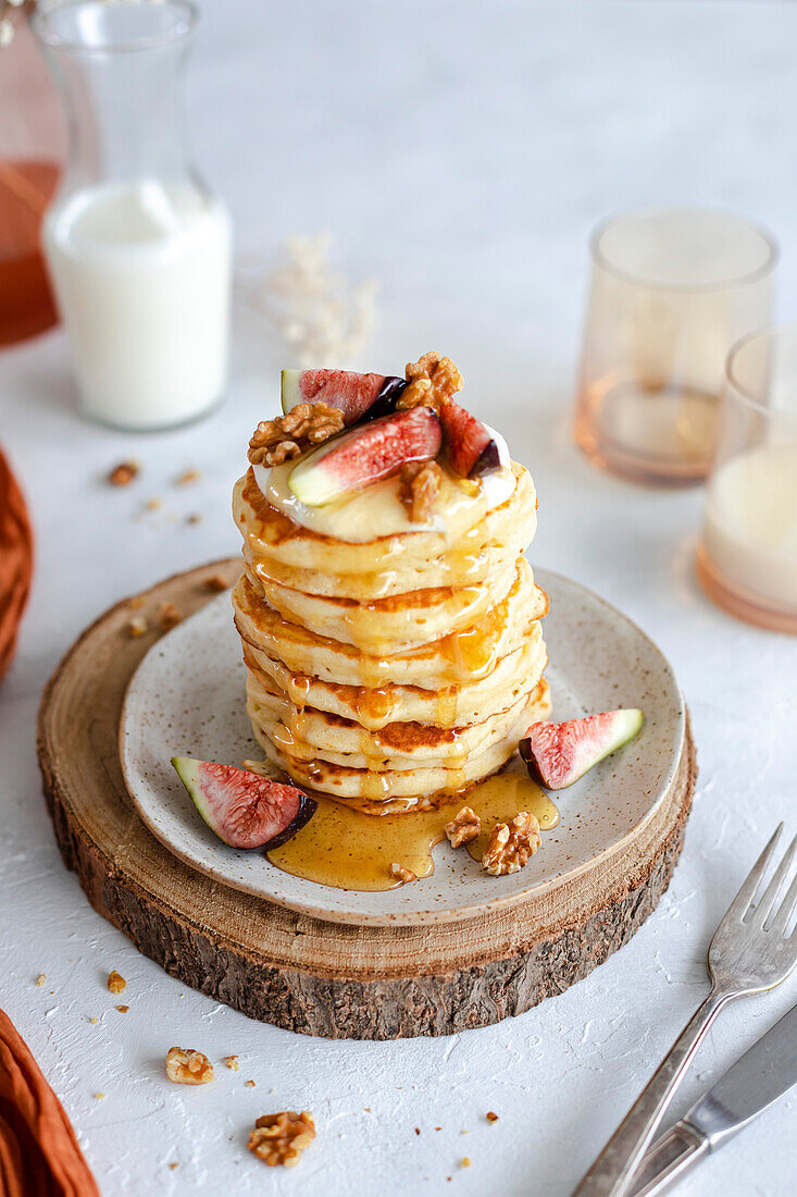 Pancake stack with cream, figs, walnuts and honey on a rustic base