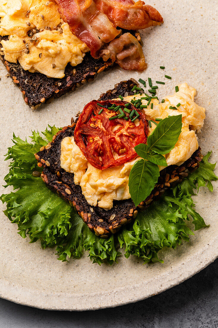 Scrambled eggs with bacon and tomato on toasted grain bread