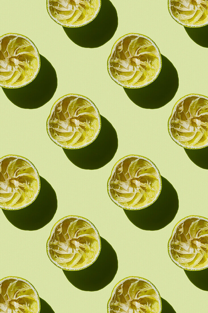 Vertikales Muster einer ausgepressten Limettenfrucht nach der Zubereitung eines frischen Getränks auf grünem Hintergrund Flatlay Food