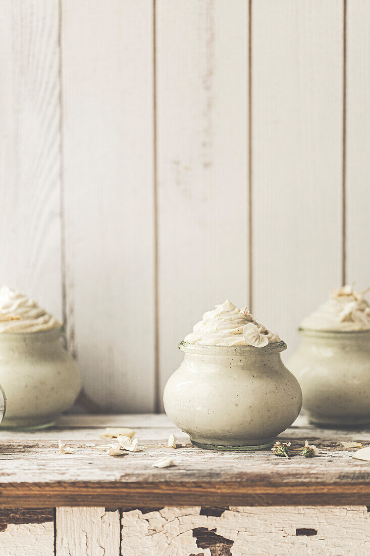 Vanille-Mousse-Dessert in einem Glas auf einem rustikalen Holzbrett serviert