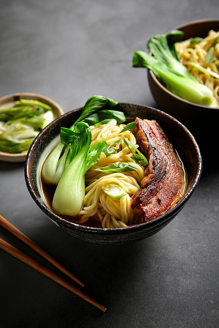 Ramen, pork belly and bok choy with a black background