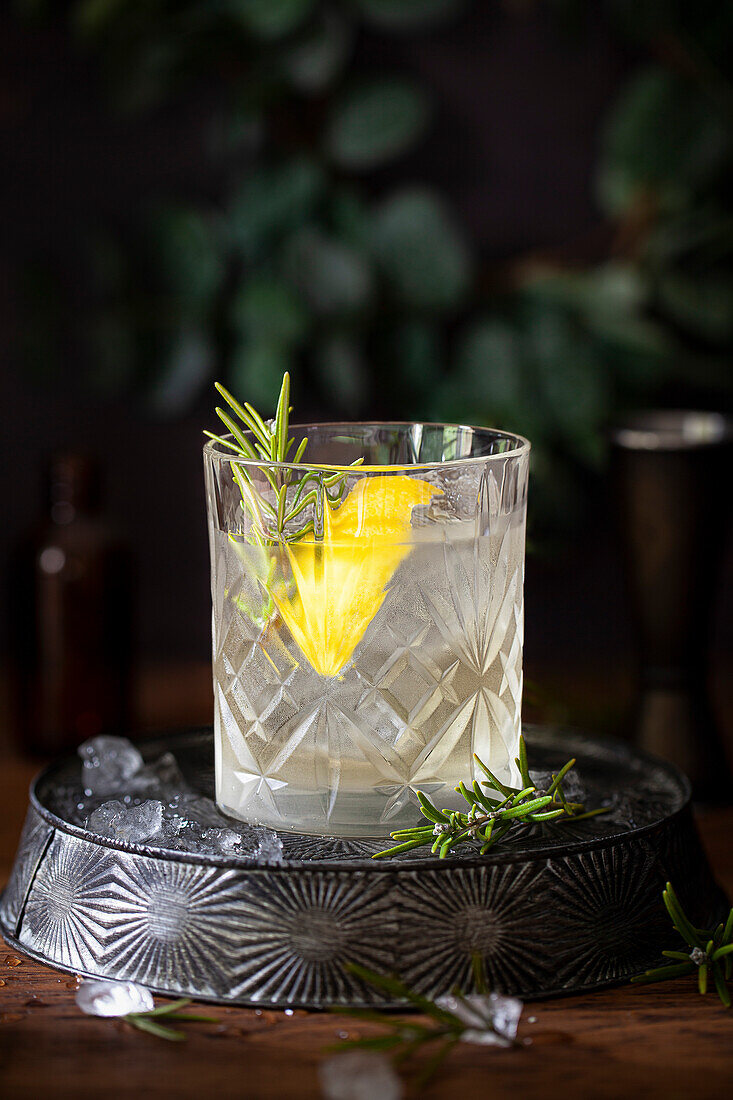 A white negroni gin cocktail with lemon and rosemary garnishes.