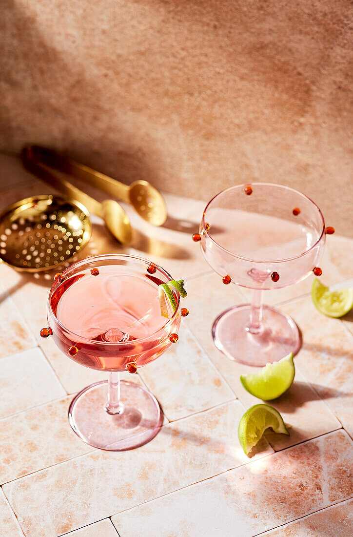 A Cosmopolitan cocktail in a traditional glass on a pink bar