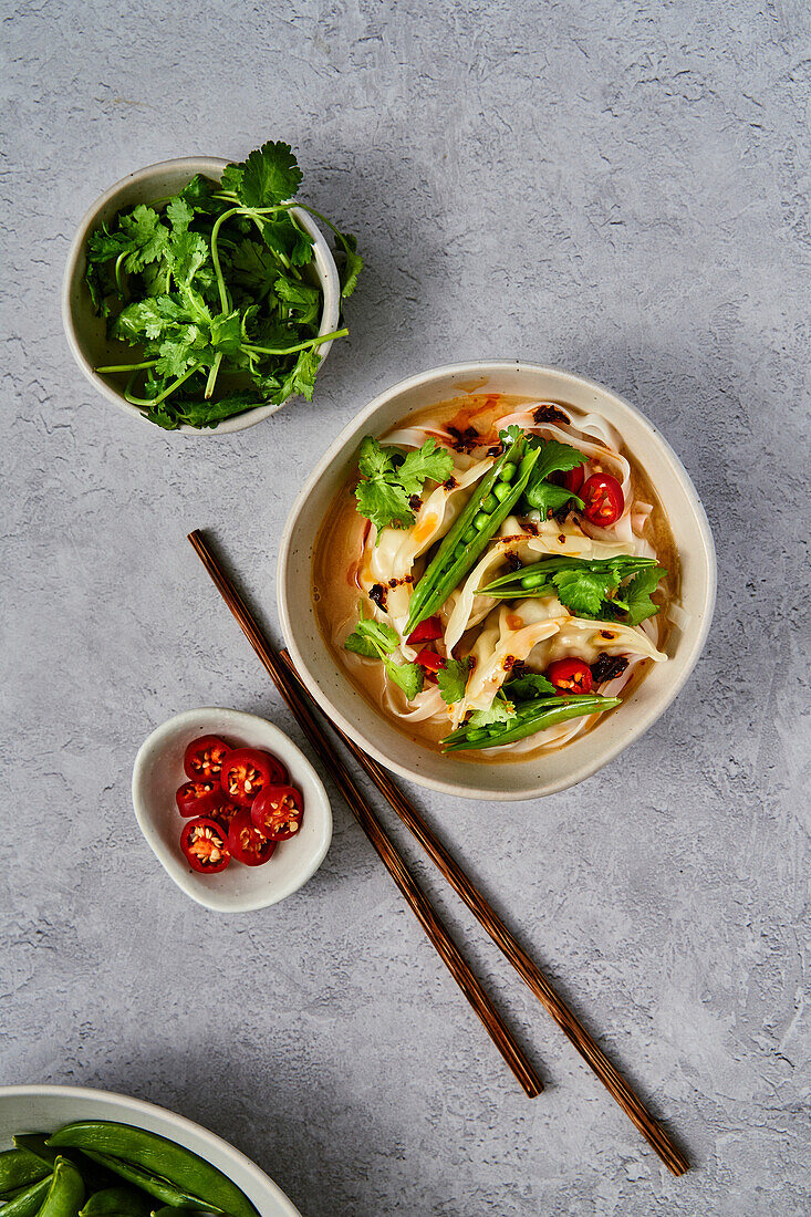 Veggie Gyoza Noodles with Sugar Snap Peas, Corainder and Chilli on grey surface