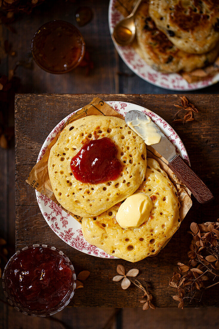 Pikelets on a plate topped with butter and jam.