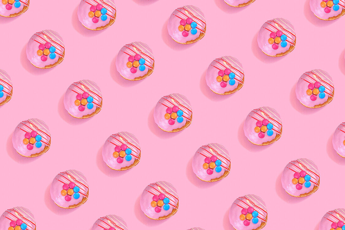 Modern retro color theme pattern of pink donuts against a pink background.