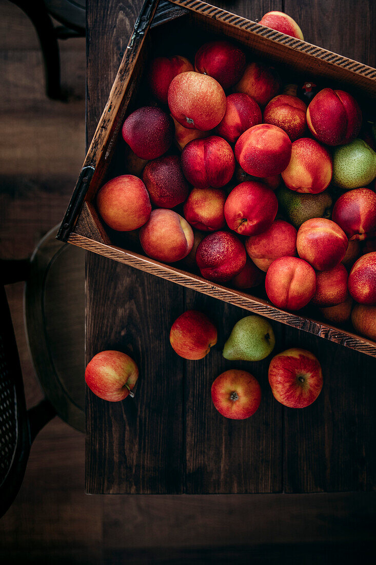 Fresh nectarines with pears in a wooden crate