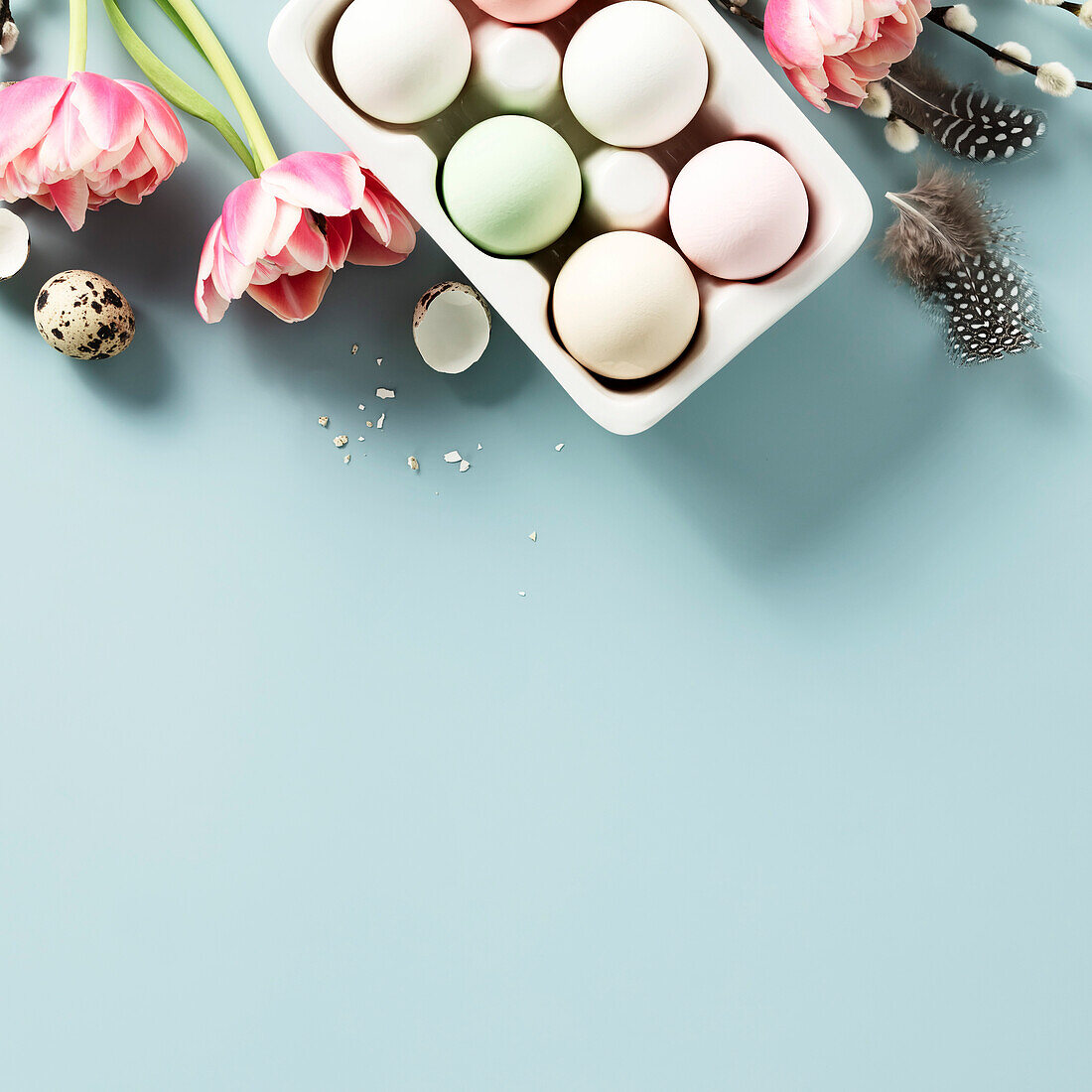 Banner. Easter background with spring flowers, eggs and feathers on a light blue background Top view flat lay copy space