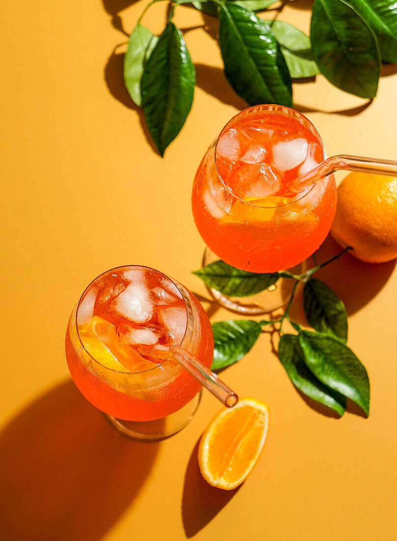 Aperol Spritz cocktail with ice, a misted refreshing drink, on an orange background, sunlight, shade, a summer drink in a wine glass