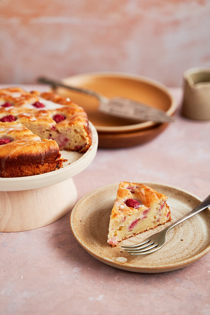 Raspberry and ricotta cake with icing on a stand with slices