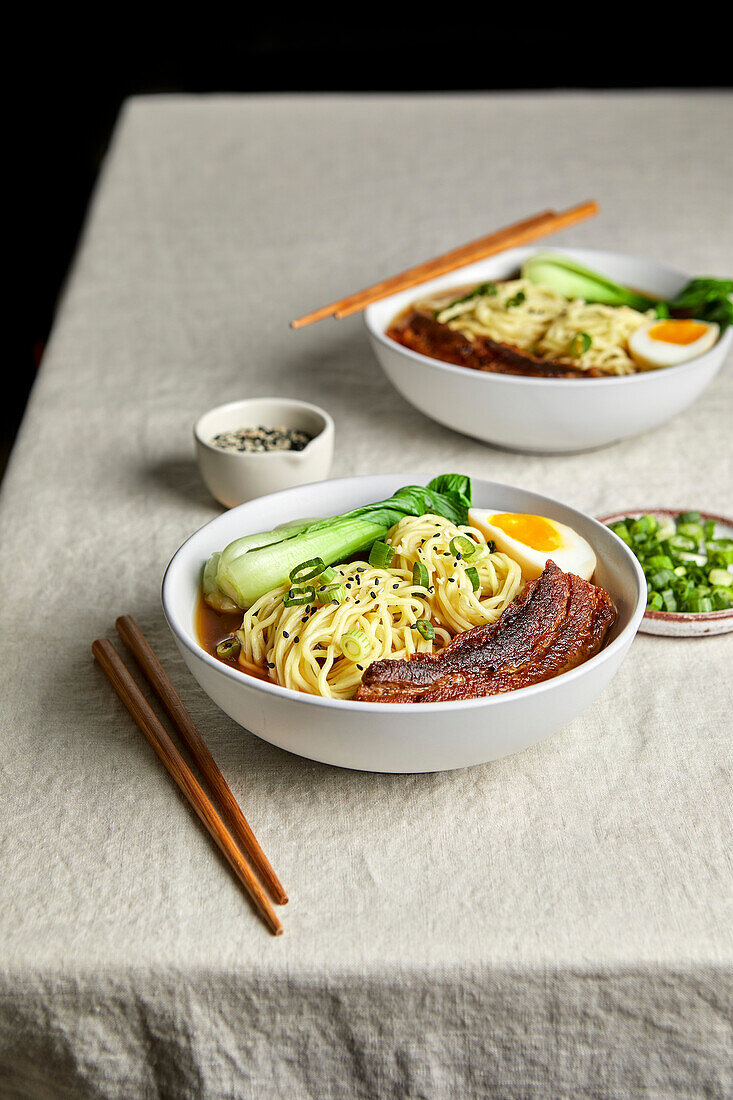 Ramen pork belly, bok choy and egg against a light-coloured neutral background