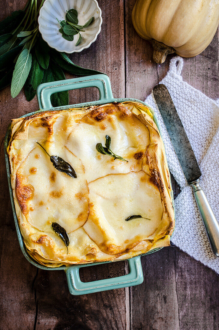 Pumpkin lasagne in a colourful cooking pan on a wooden table