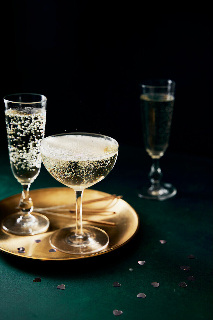 Prosecco glasses and golden plate on a green background