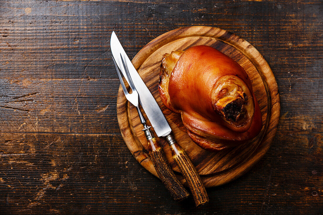 Gebratene Schweinshaxe mit Eisbein auf Holzbrett