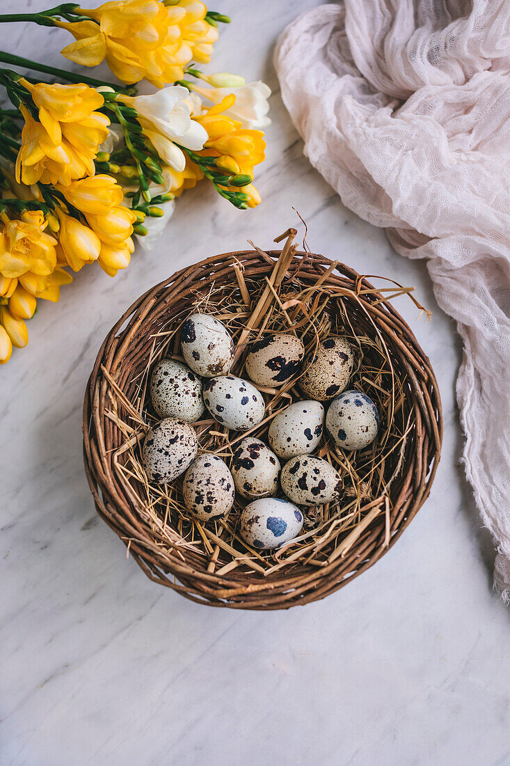Quail eggs in a basket on a white marble background