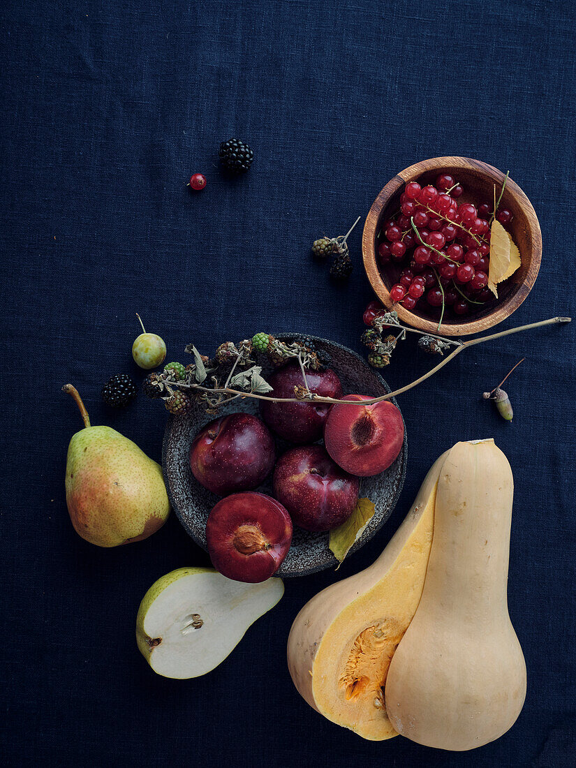 Herbstliche Lebensmittelzutaten auf dunkelblauem Hintergrund mit Kopierraum. Flat-Lay von Herbstgemüse, Beeren und Pilzen vom lokalen Markt. Vegane Zutaten