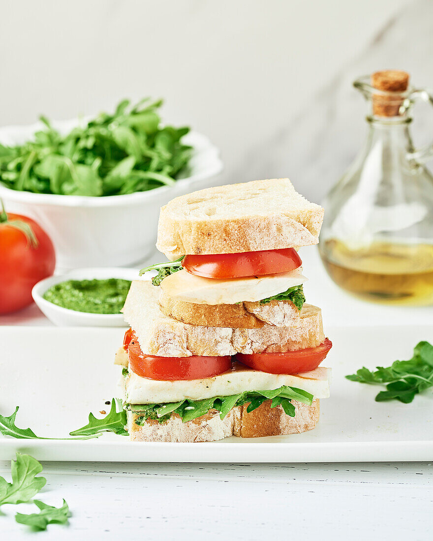 Gestapeltes veganes Caprese-Sandwich auf einem weißen Teller