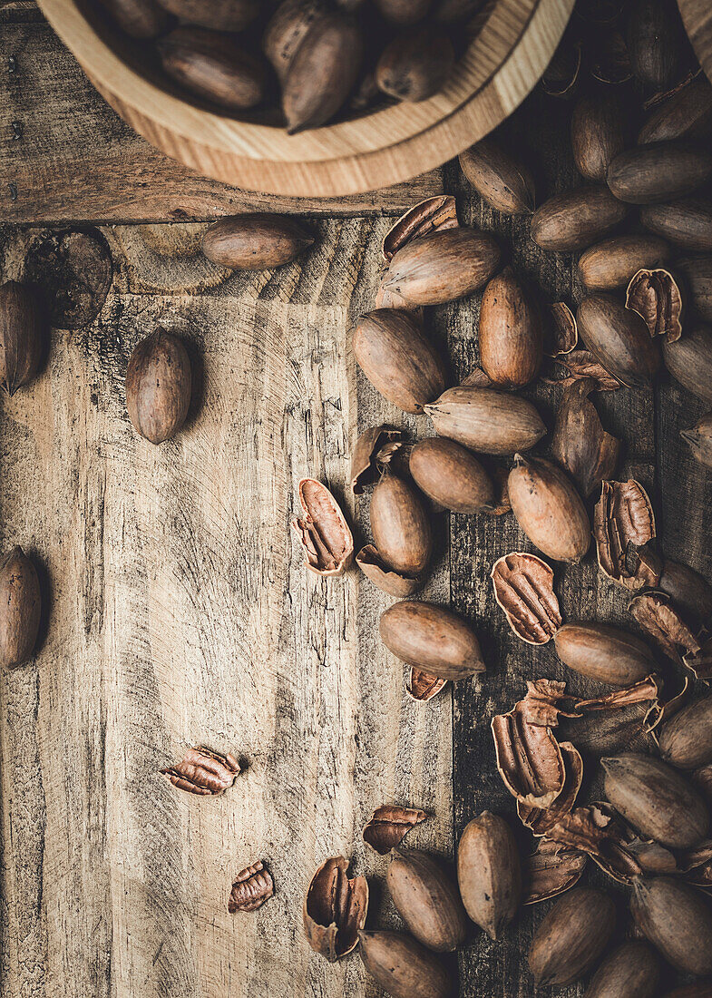 Fresh pecans and broken shells on a rustic wooden background