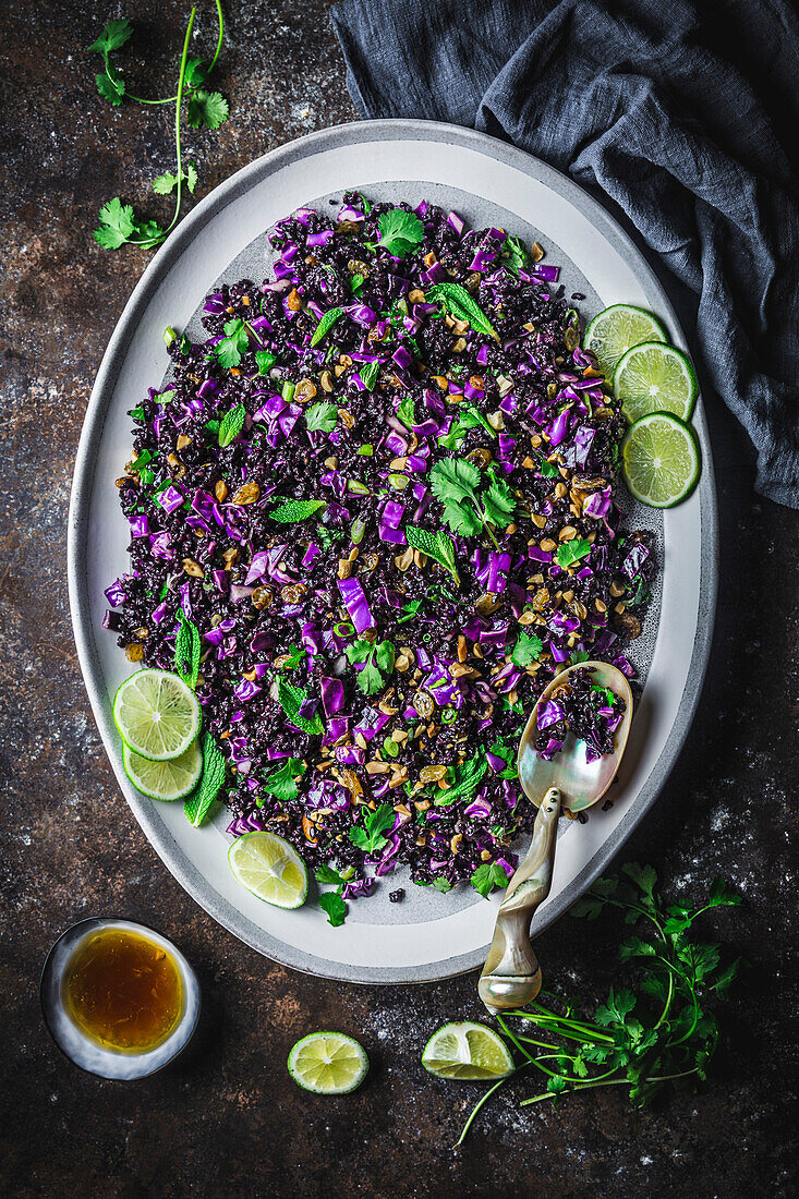 Black Rice, red cabbage and herb Salad on oval platter with sliced limes, coriander and napkin