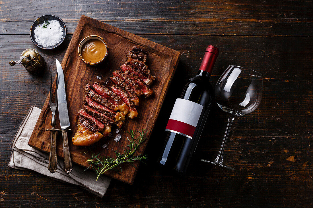 Grilled steak strips with pepper sauce and a bottle of red wine on a wooden base