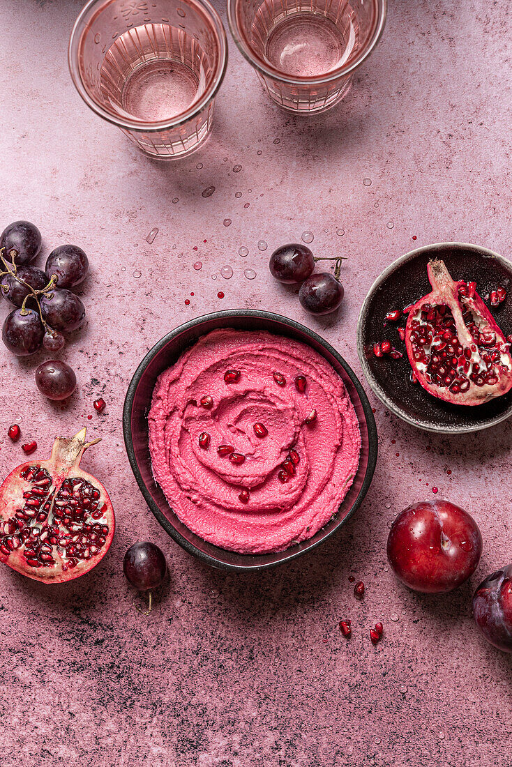 Schale mit rosa Hummus und frischem Obst