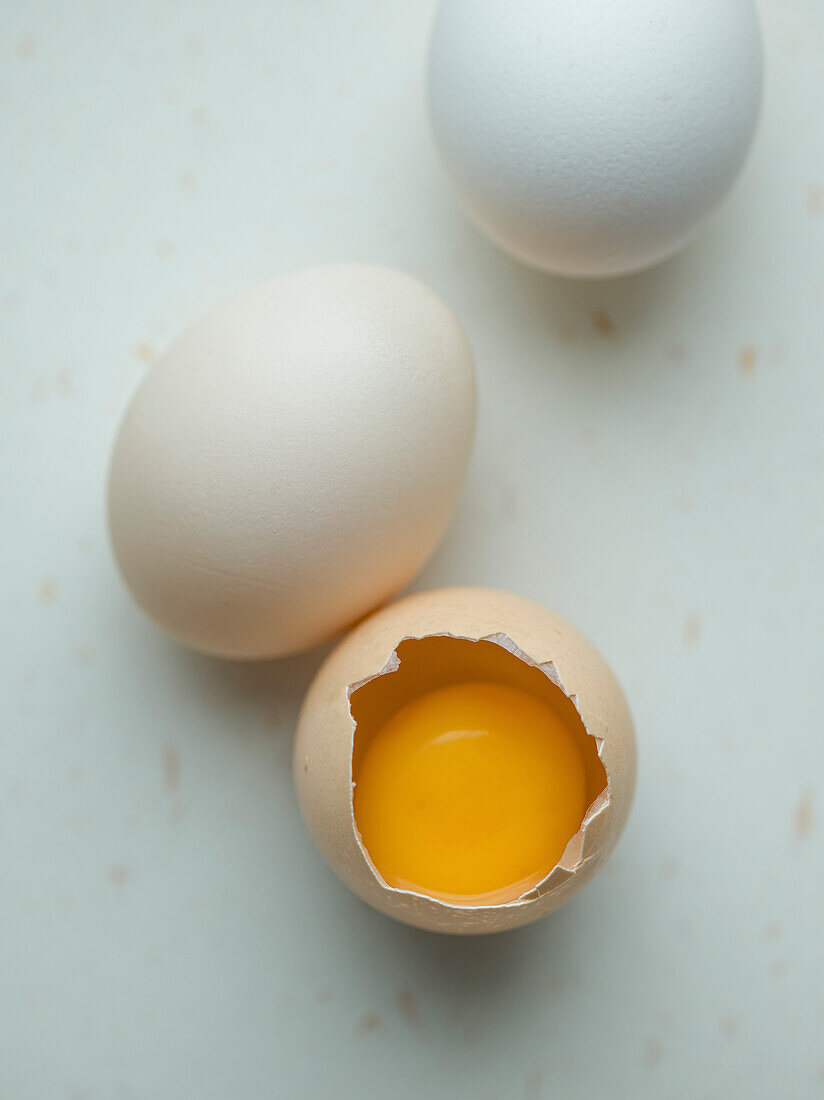 Close-up, three chicken eggs on a white background, one cracked open
