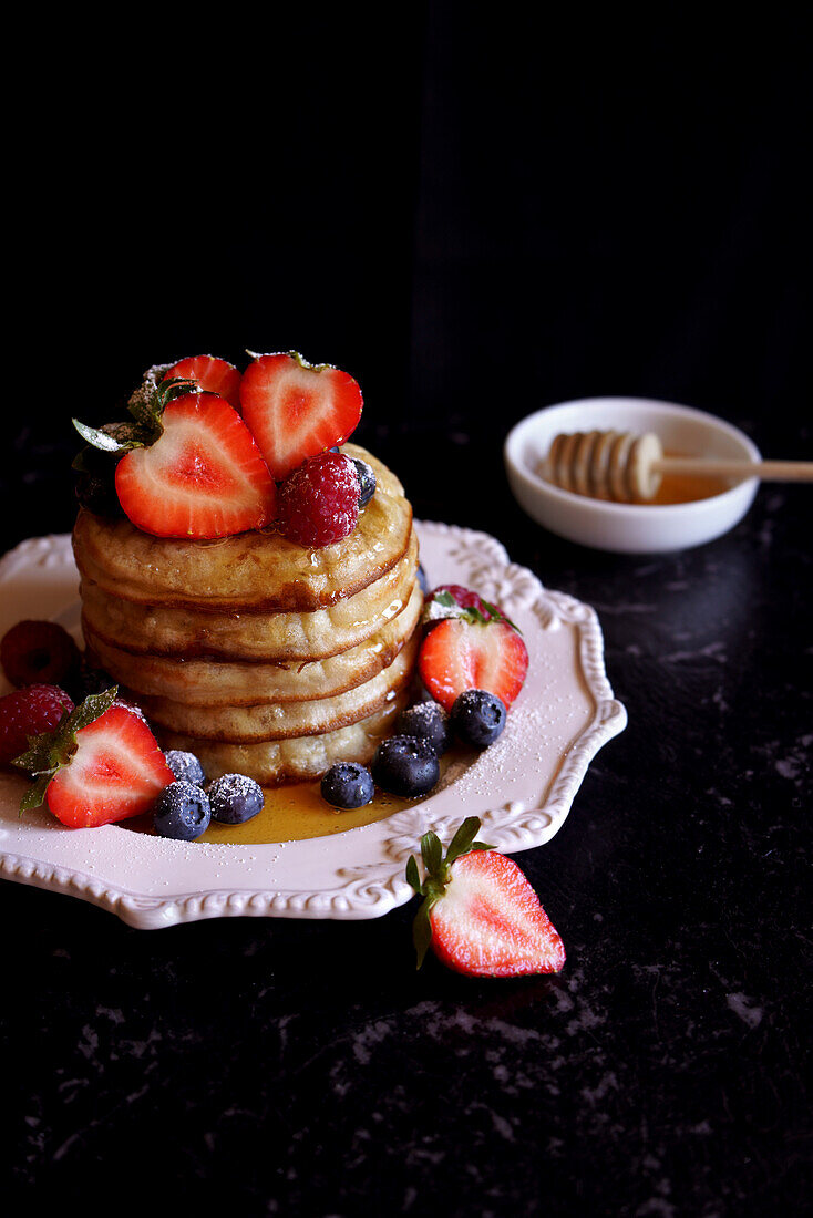 Stack of English crumpets with berries and honey