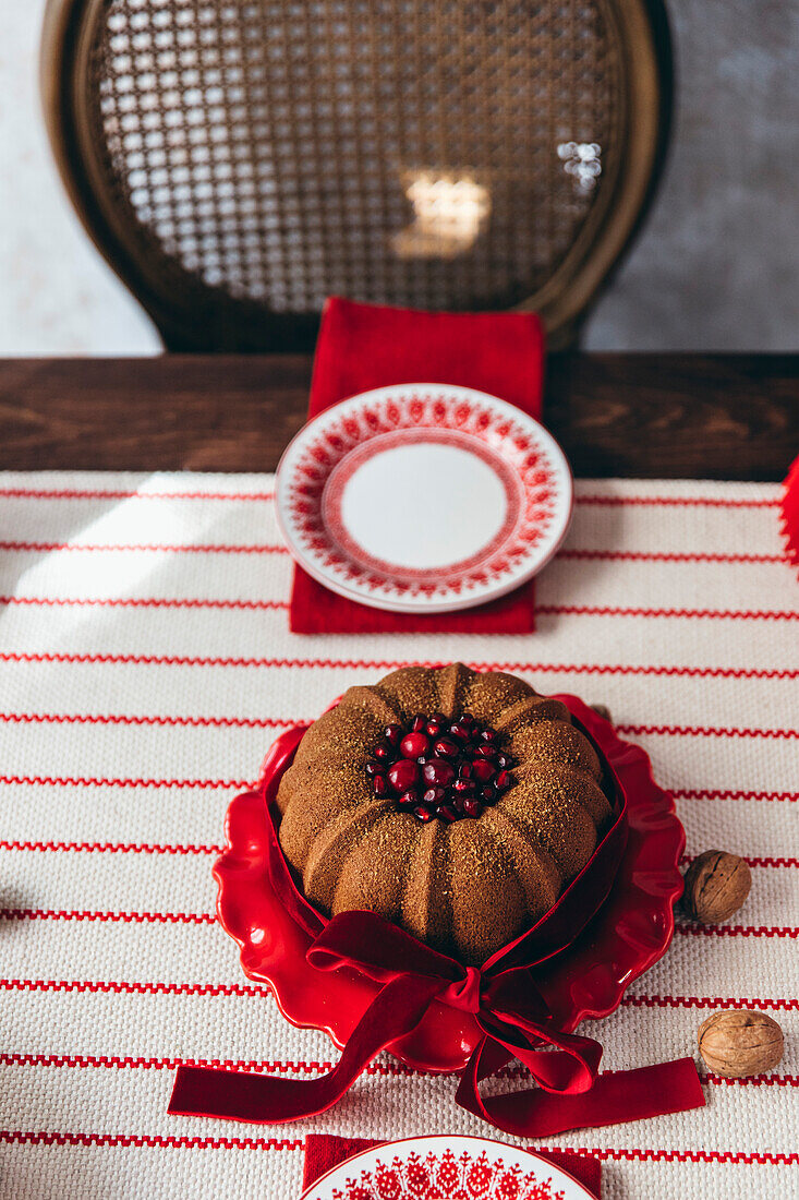 Traditional Christmas bundt cake served on a table with a red ribbon. Filled with cranberries.