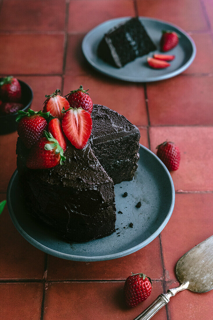 Schokoladenkuchen mit frischen Erdbeeren vor einem Terrakotta-Hintergrund