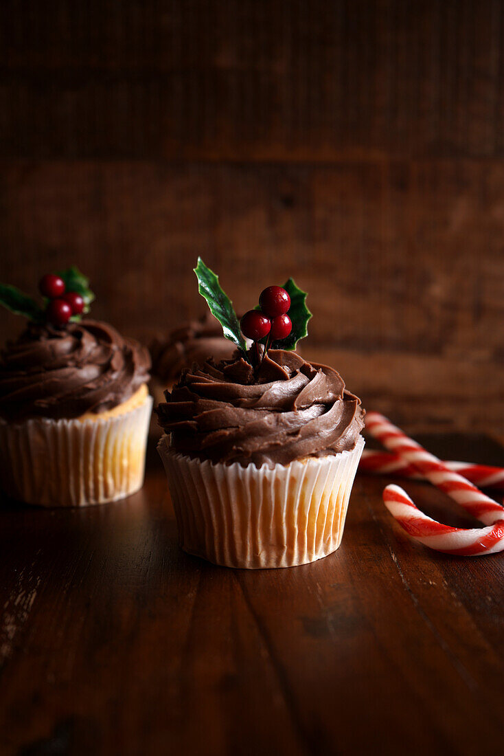 Christmas holiday chocolate cupcakes against a dark wood background. Negative copy space