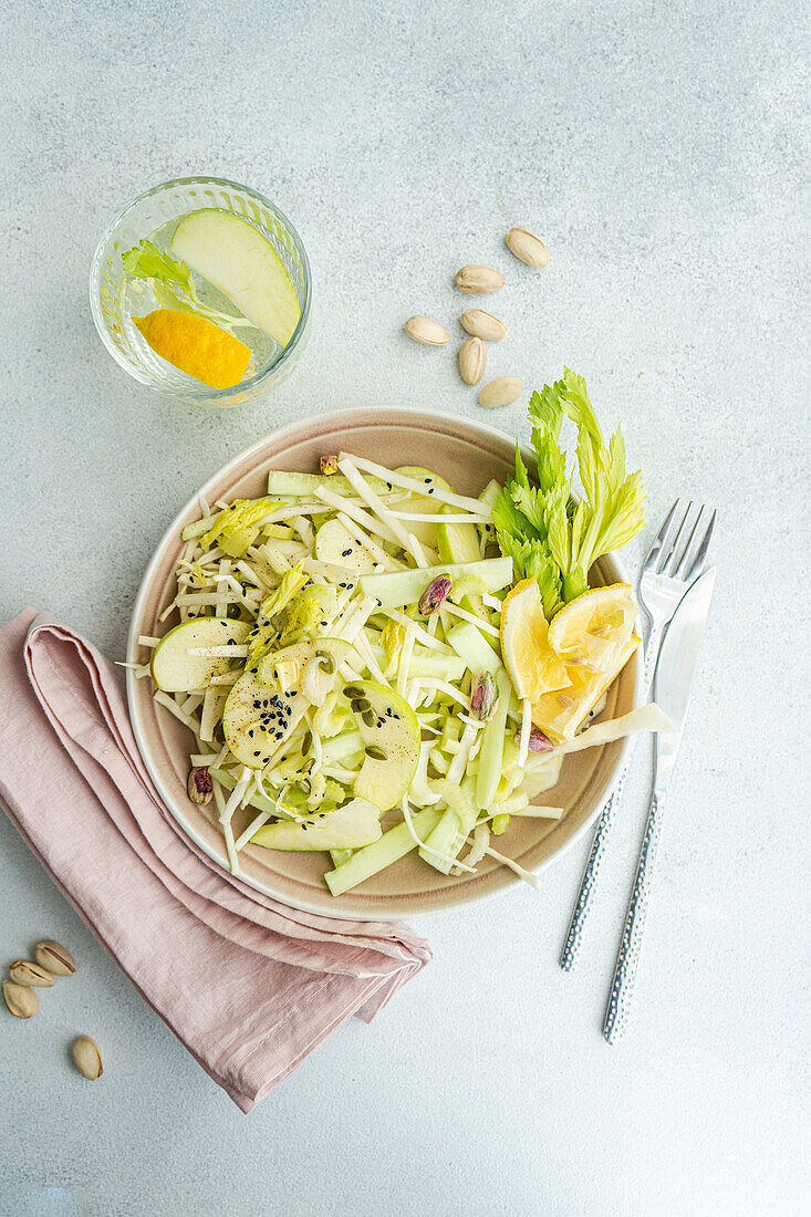 Healthy celery salad with apples and seeds in the bowl on a concrete background, seen from above