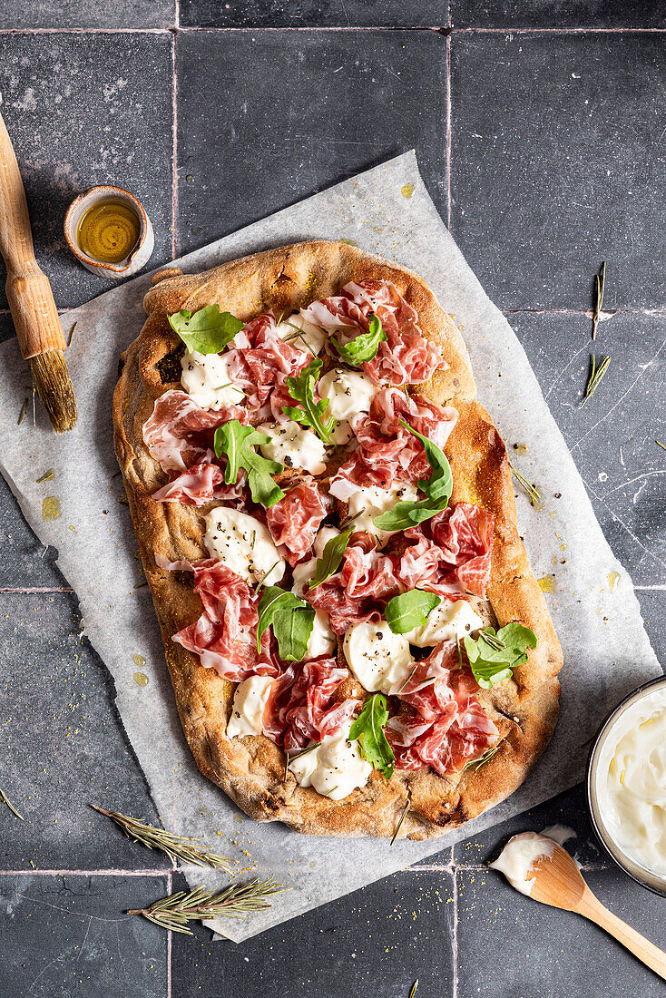 Pizza with prosciutto, cheese and arugula
