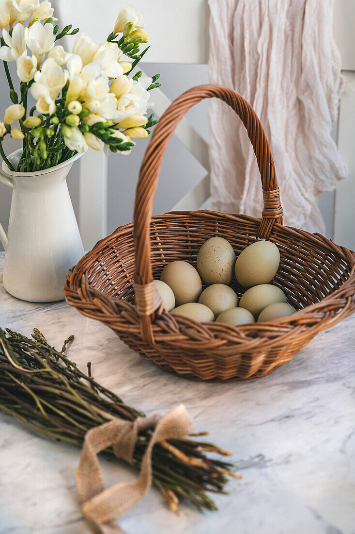Green eggs in a wicker basket on a white marble table