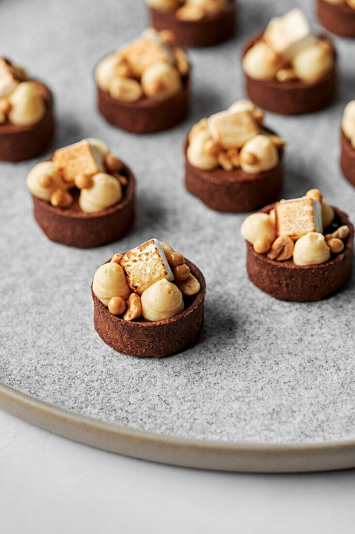 Dark chocolate tarts with peanut butter mousse, toasted marshmallows, and caramel pearls