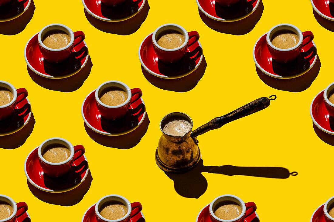 Espressokaffee in roter Tasse und kupferner Cezva auf gelbem Hintergrund Muster