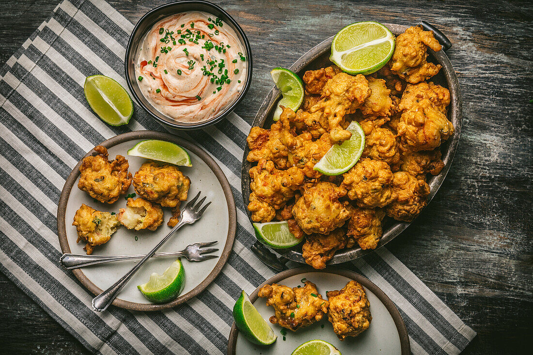 Shrimp fritters in basket and plate with dipping sauce and lime