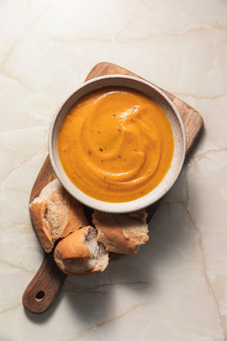 Butternut squash soup and baguette on a wooden board