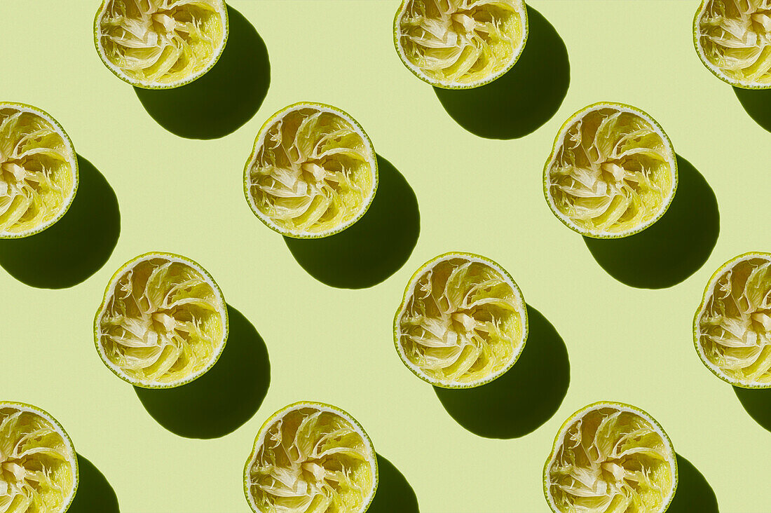 Horizontales Muster einer ausgepressten Limettenfrucht nach der Zubereitung eines frischen Getränks auf grünem Hintergrund Flatlay Food